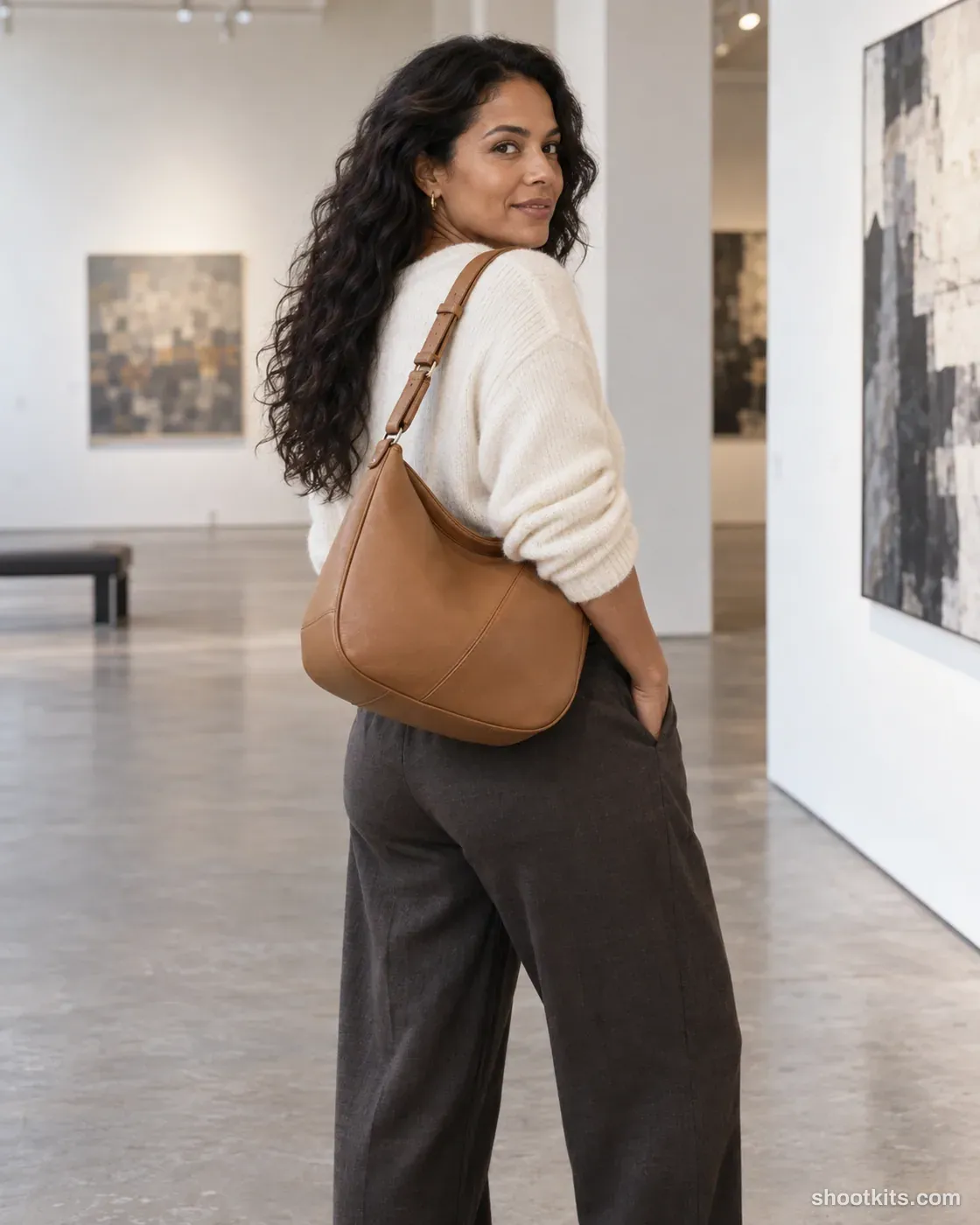 Gallery shoulder turn: bag photo made with ChatGPT. Contemporary gallery with neutral walls.