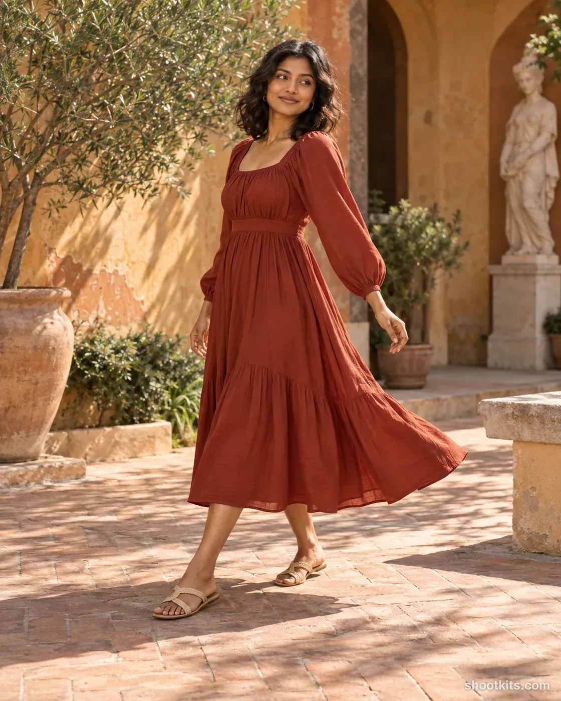Woman turning in a rust-red midi dress in a sunlit ochre museum courtyard.